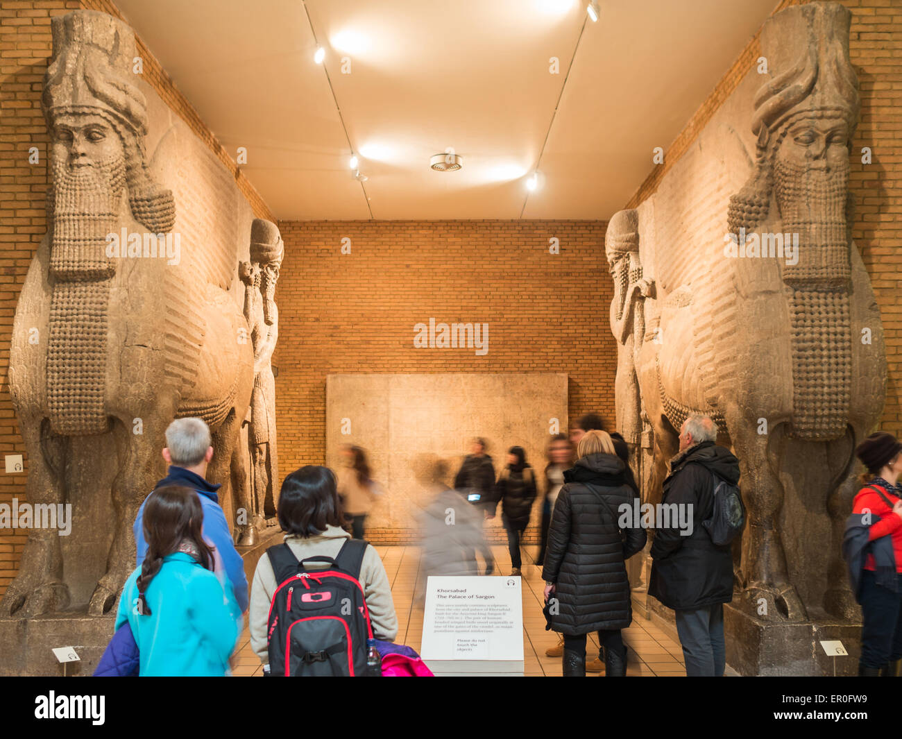 Visitatori dal Gateway assiro con testa umana leoni alati 'Lamassu' presso il British Museum Foto Stock