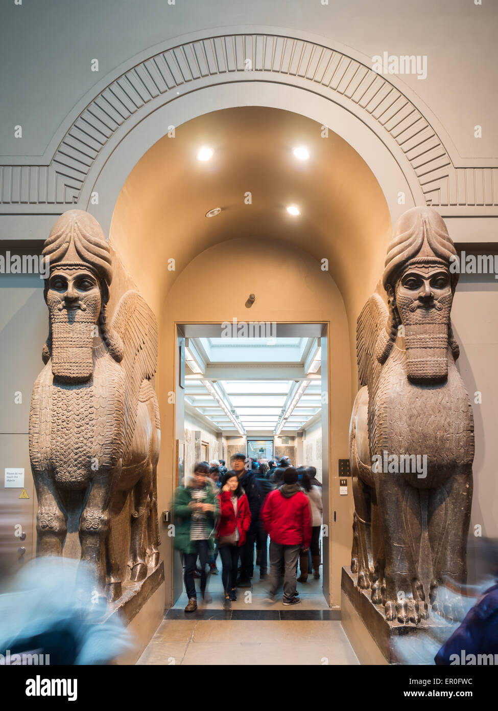 Visitatori di passaggio dal Gateway assiro con testa umana leoni alati 'Lamassu' presso il British Museum Foto Stock