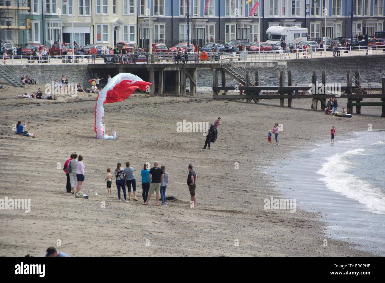 Su guardato guardare come un parapendio atterra sulla spiaggia nord in Aberystwyth. Foto Stock