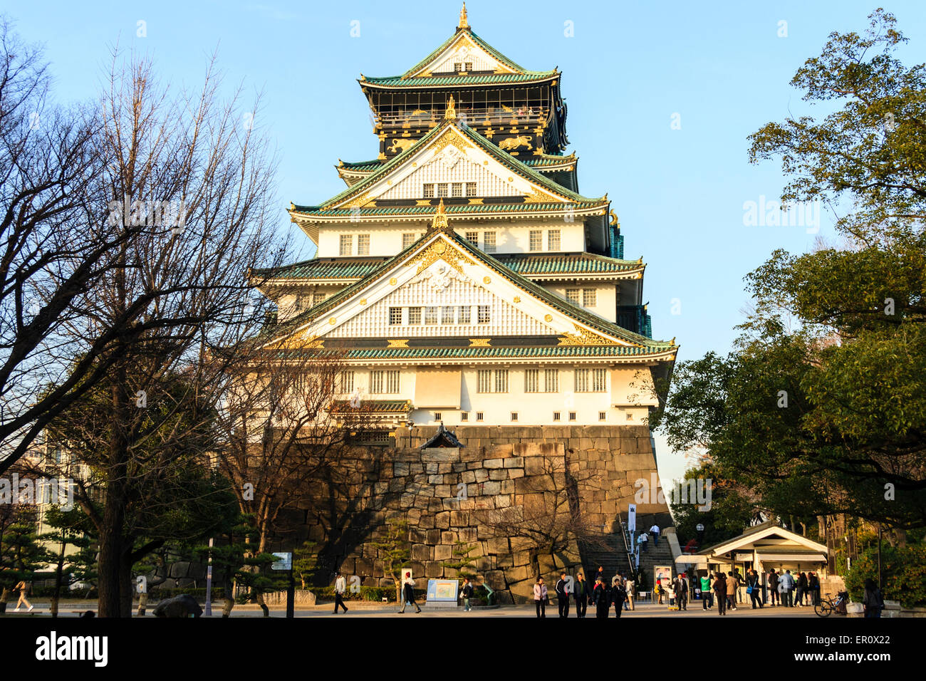 Vista invernale all'ora d'oro dell'imponente torrione in stile borogata del Castello di Osaka con le sue scuderie e la torre di guardia superiore contro il cielo blu chiaro. Foto Stock