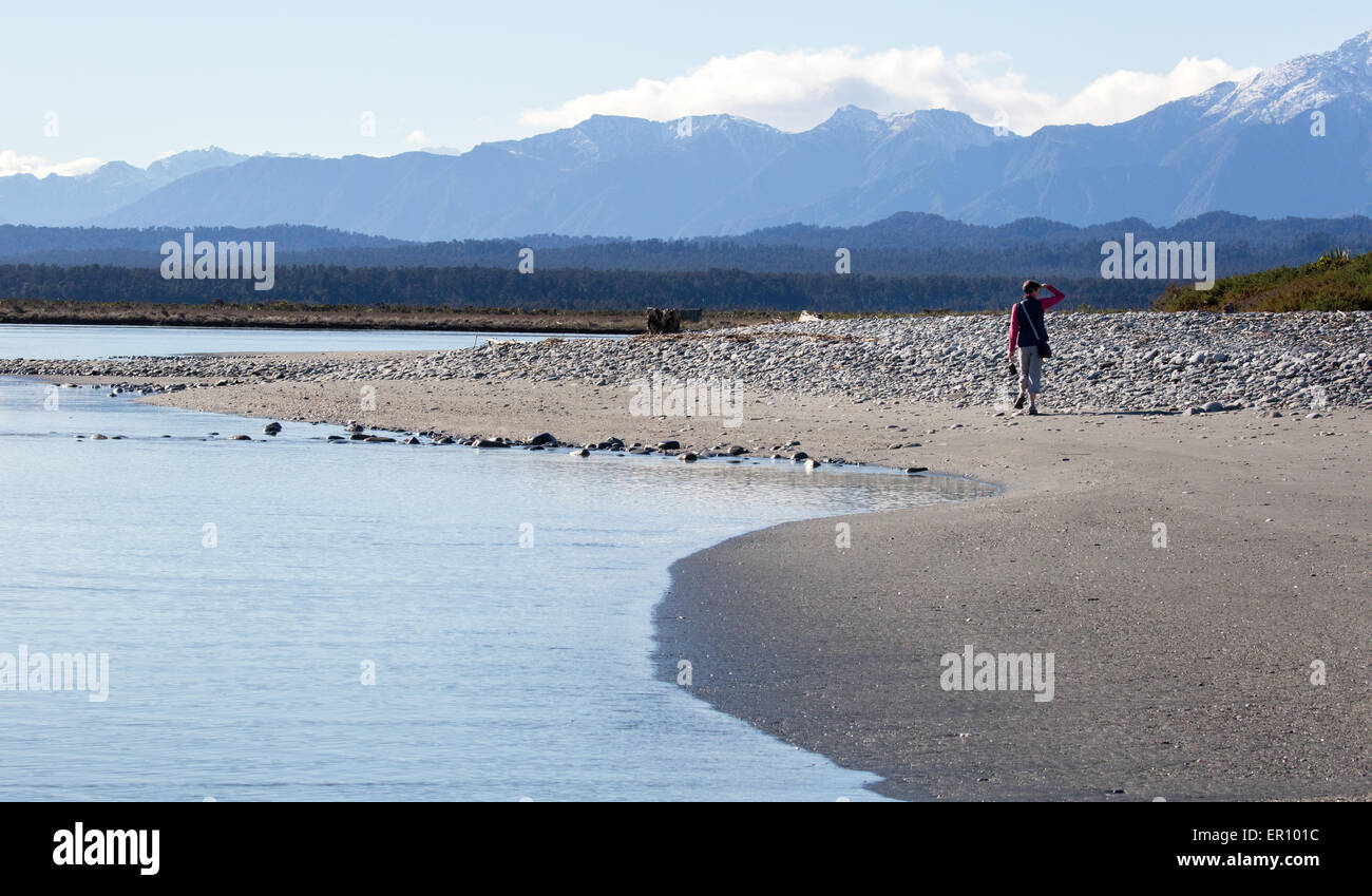 Walker al seaward ingresso alla Laguna Okarito guardando verso le Alpi del Sud nell'Isola Sud della Nuova Zelanda Foto Stock