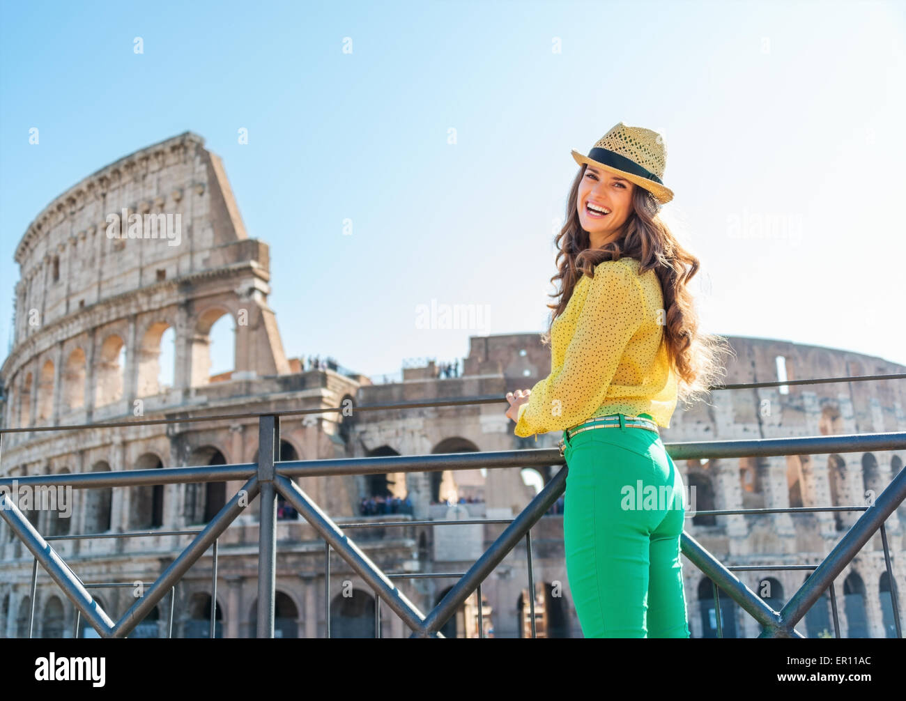 Donna sorridente turista sta ammirando il Colosseo a distanza su una calda giornata estiva a Roma. Foto Stock