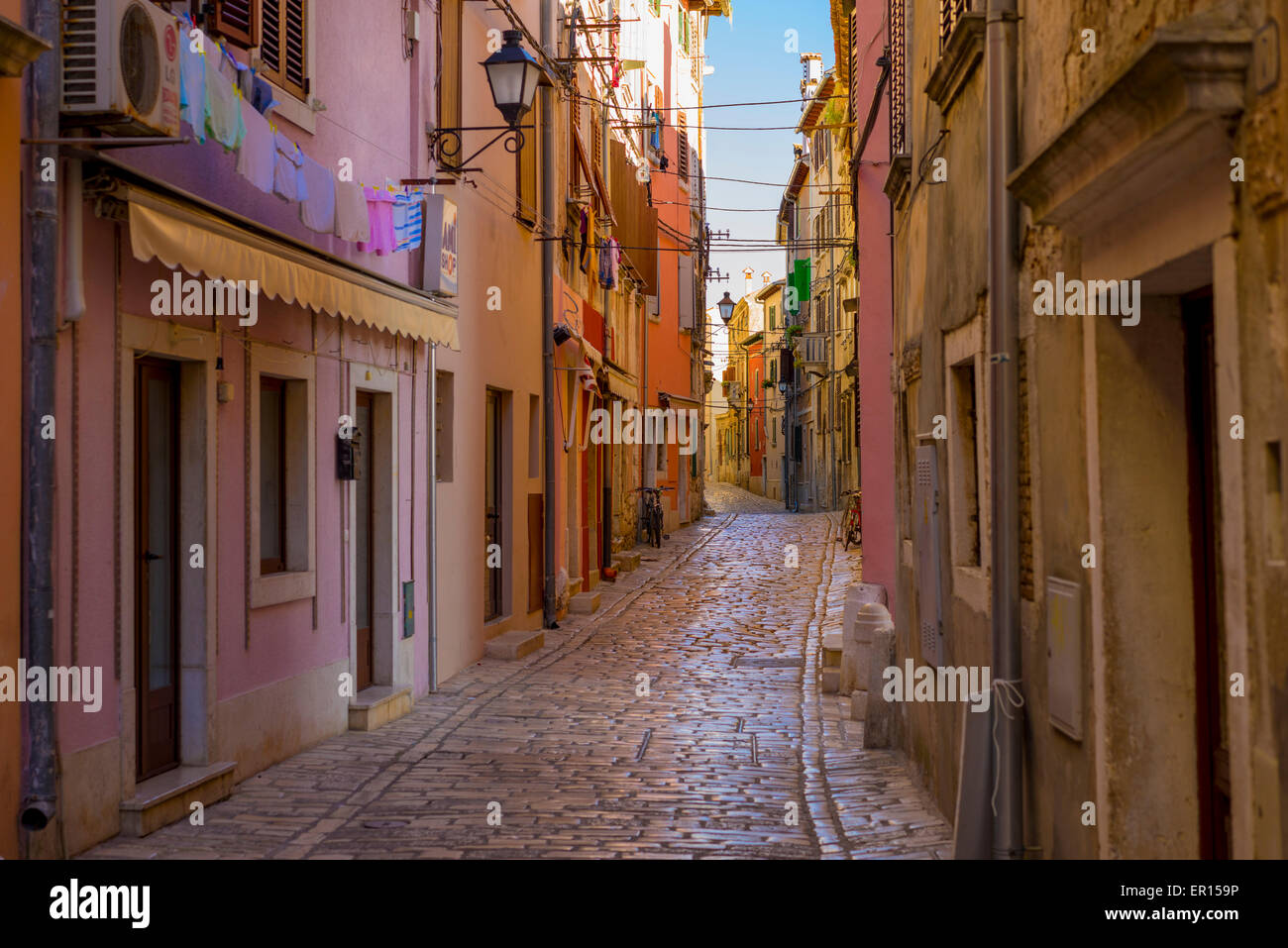 La mattina presto fotografia di coloratissimi Rovigno street con luccicanti ciottoli, ornate street e lampade in stile veneziano di edifici Foto Stock