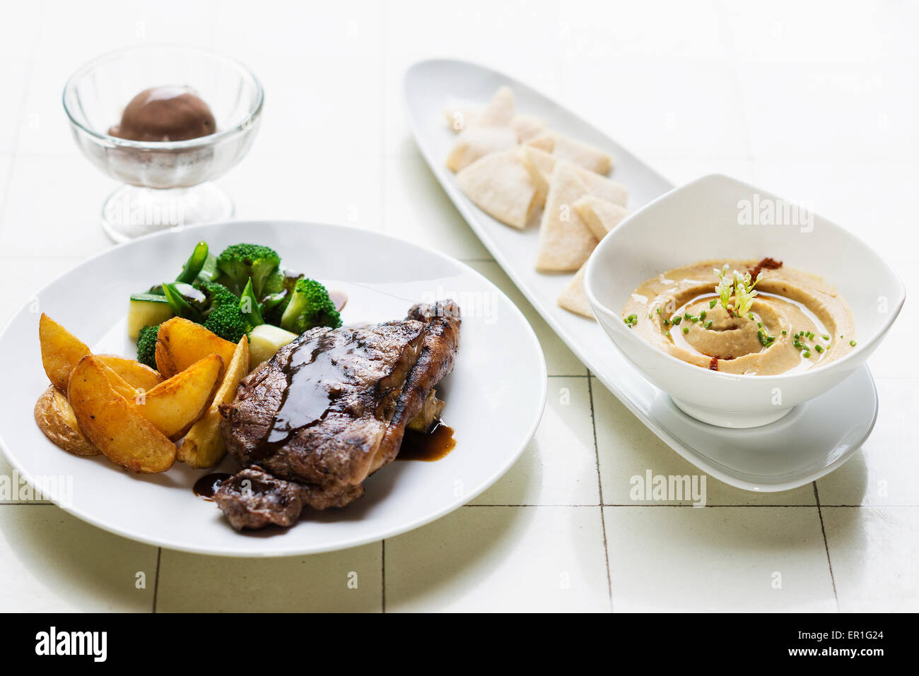 Bistecca alla griglia pasto con hummus dip motorino di avviamento sul tavolo Foto Stock