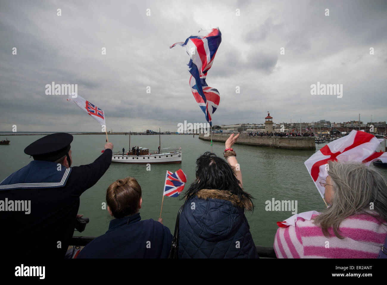 Spettatori ondata di bandiere e di allegria come essi accolgono con favore il ritorno di Dunkirk navi poco indietro nel Porto di Ramsgate. Le navi hanno restituito dopo la vela a Dunkerque per commemorare il settantacinquesimo anniversario di funzionamento dinamo. Foto Stock