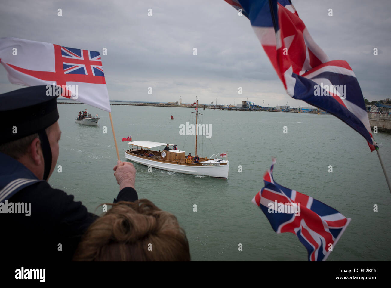 Spettatori ondata di bandiere e di allegria come essi accolgono con favore il ritorno di Dunkirk navi poco indietro nel Porto di Ramsgate. Le navi hanno restituito dopo la vela a Dunkerque per commemorare il settantacinquesimo anniversario di funzionamento dinamo. Foto Stock