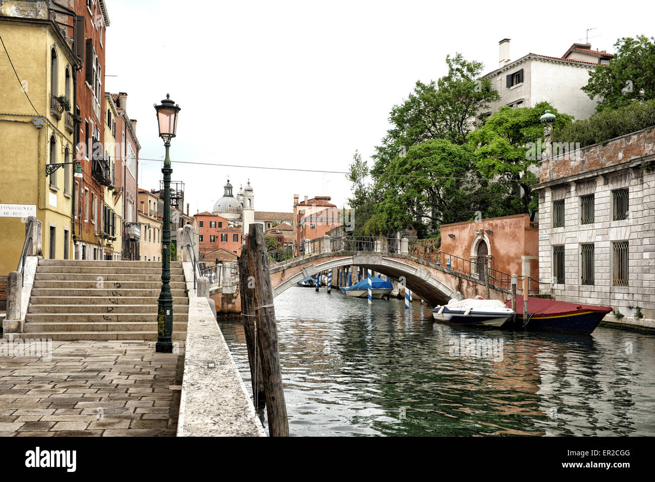 Idillica scena italiana con piedi ponte che attraversa il Canal foderato con edifici bassi, Venezia, Italia Foto Stock