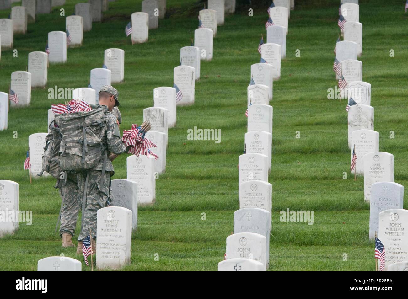 Un esercito americano soldato da la vecchia guardia bandiere posti nella parte anteriore della tomba di siti in onore del Memorial Day al Cimitero Nazionale di Arlington, Maggio 21, 2015 in Arlington, Virginia. La vecchia guardia ha condotto le bandiere, quando una bandiera americana è collocato in corrispondenza di ogni lapide, dal 1948. Foto Stock