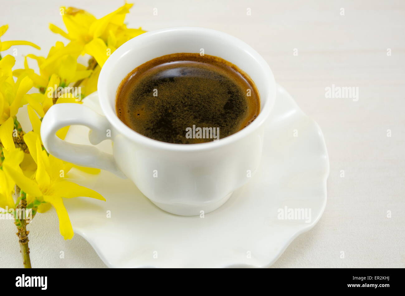 White tazza di caffè su di un tavolo di legno decorato con fiori Foto Stock