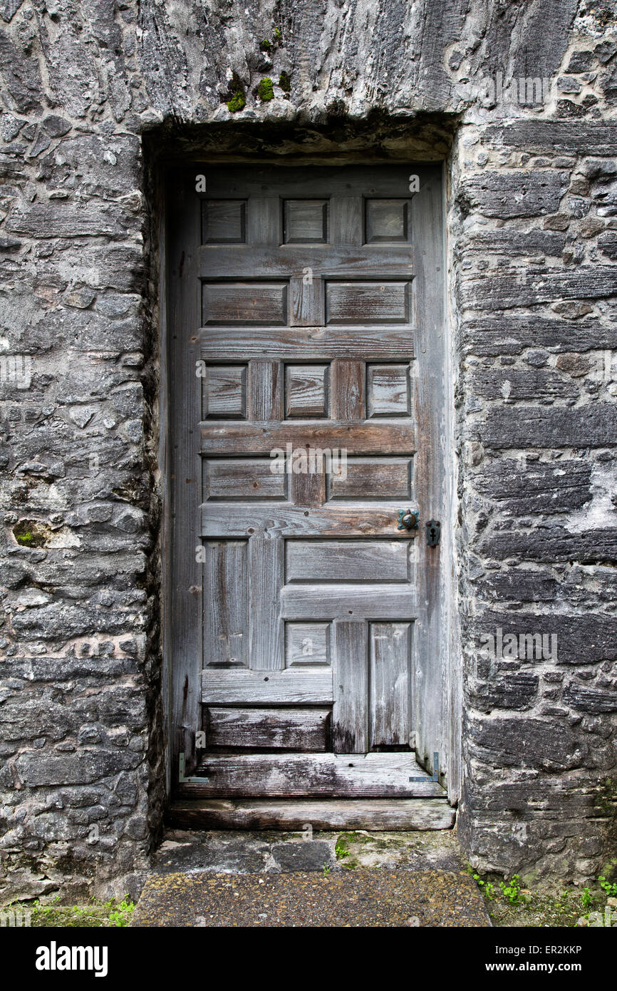 Tenuto in pietra entrata, invecchiamento vecchio legno pannello porta. Foto Stock