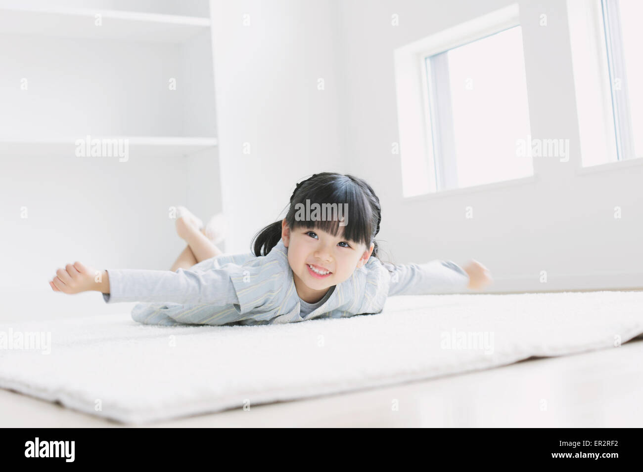 Elementare di età ragazza posa sul pavimento mediante la finestra Foto Stock