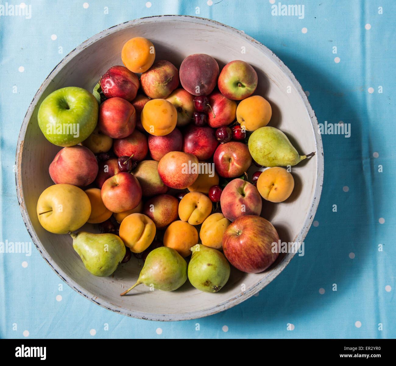 Una ciotola di frutti, su un tavolo blu runner Foto Stock