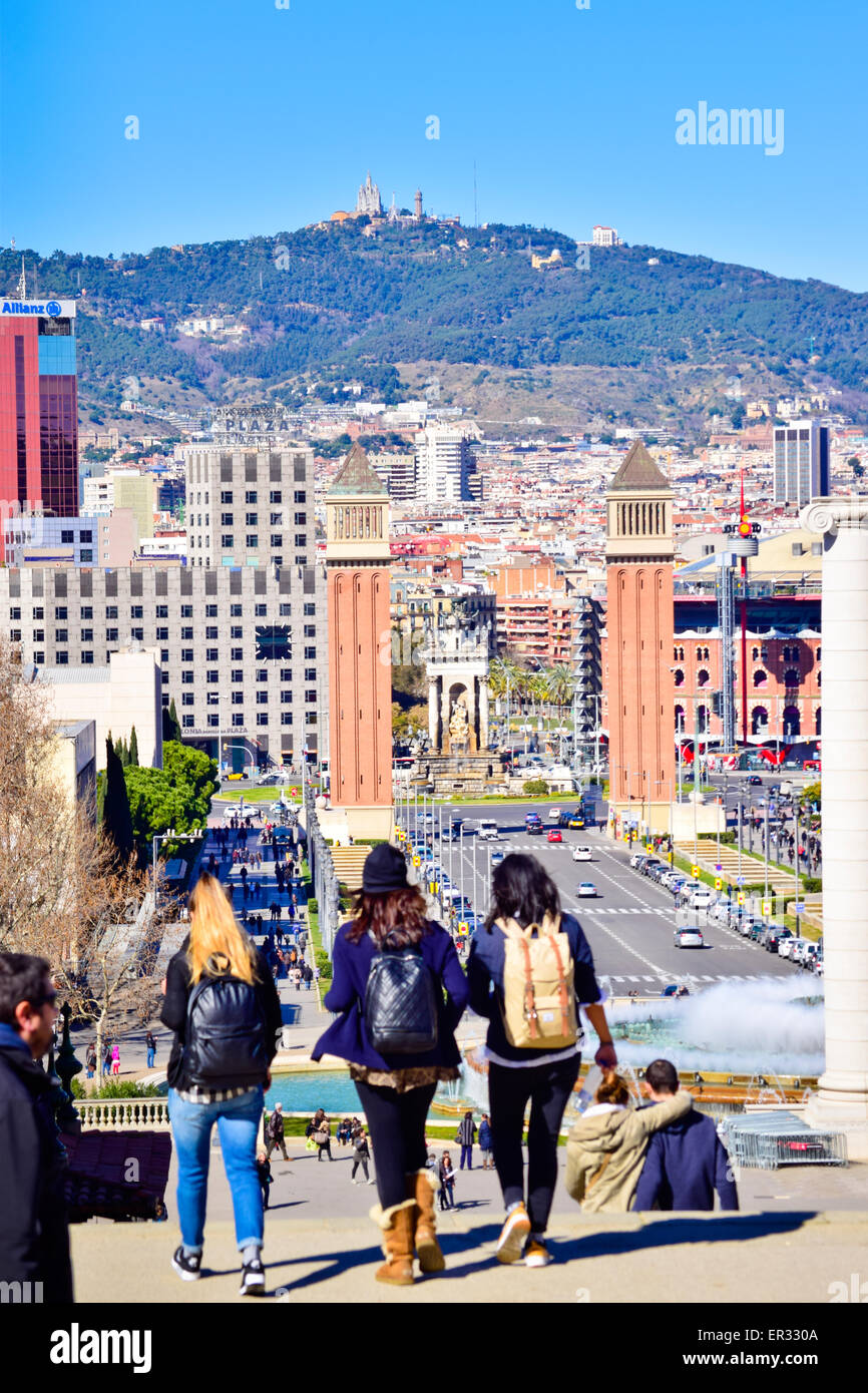 La gente camminare all'indietro. Cityscape sfondo. Reina Maria Cristina avenue e due torri di Venezia. Barcellona, in Catalogna, Spagna. Foto Stock