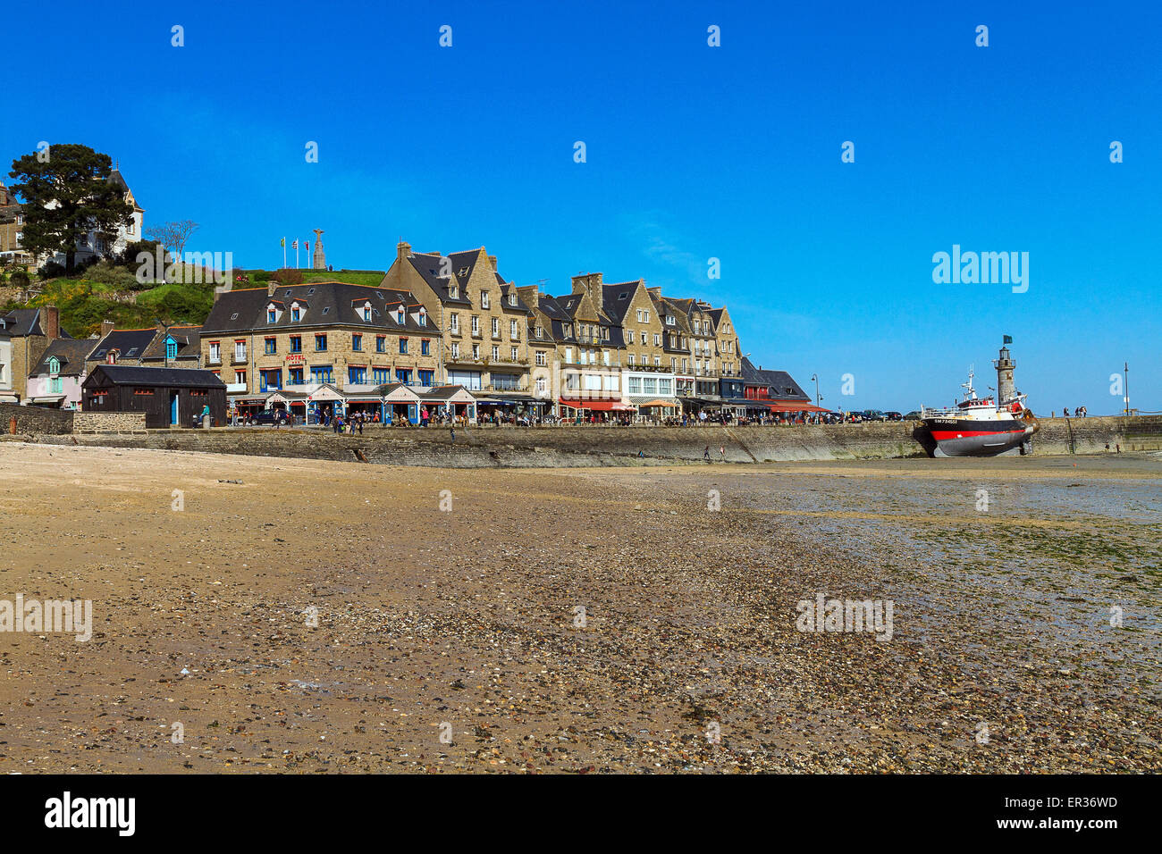 Cancale (Francia, Bretagna Cancale), il panorama della spiaggia cittadina, e sullo sfondo le case di il lungomare e il porto con una barca da pesca in secca a causa della bassa marea. Foto Stock
