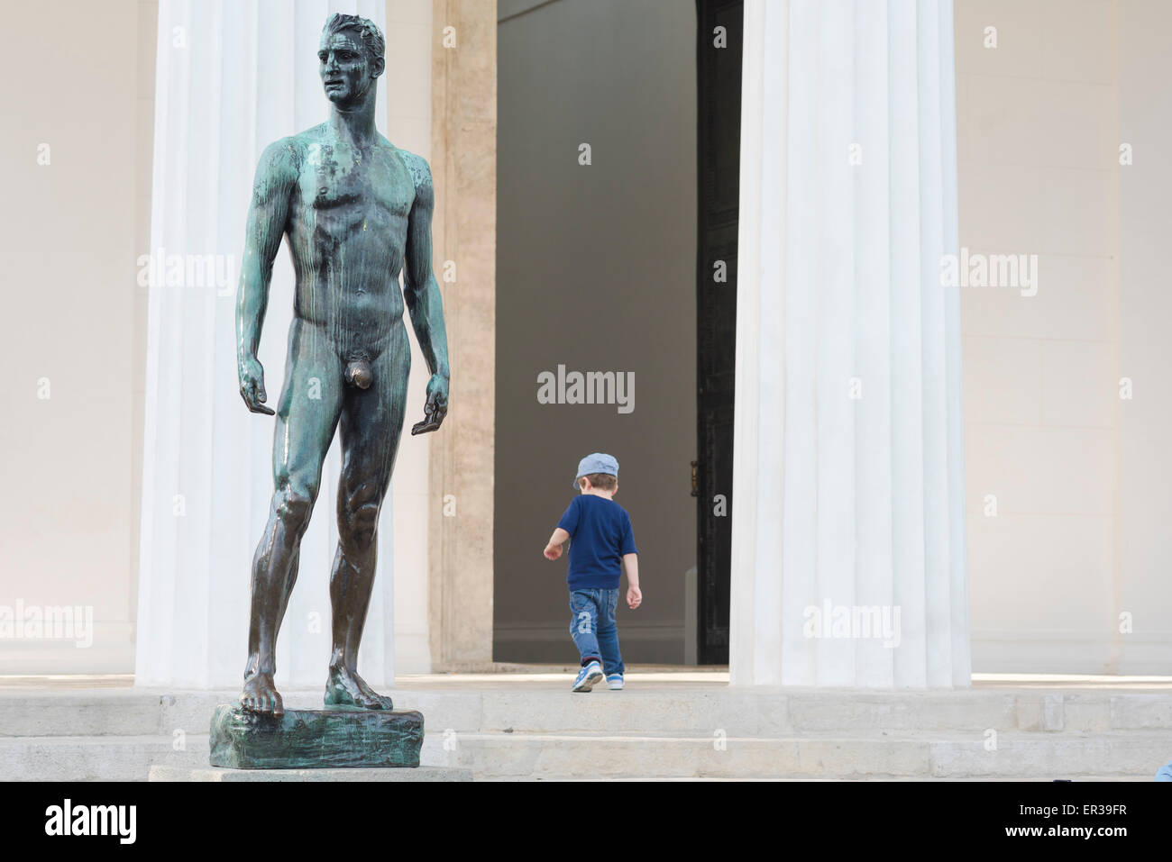 Uomo e ragazzo, vista di un bambino che cammina davanti a una scultura di un atletico fuori dal Tempio di Theseus nel Volksgarten a Vienna, Vienna, Austria. Foto Stock