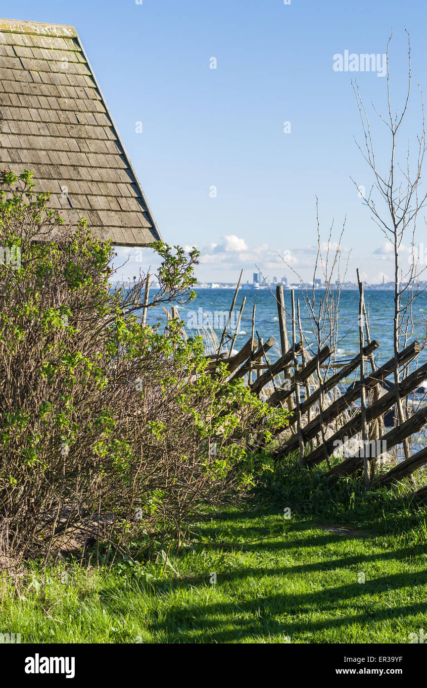 Rustico e siepe sulla riva del mare e città sullo sfondo Foto Stock
