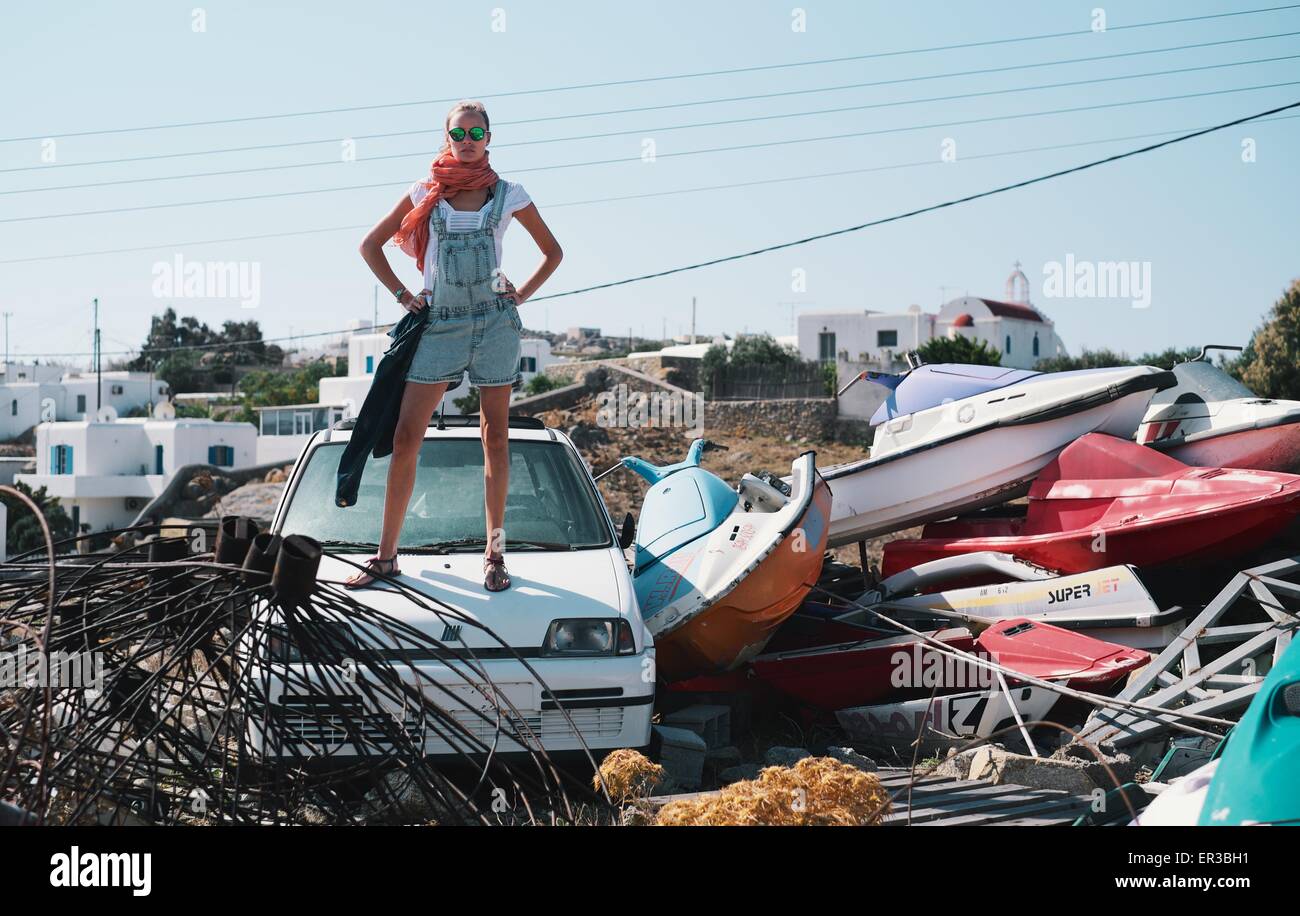 Donna in piedi su auto nel cortile di scarto Foto Stock