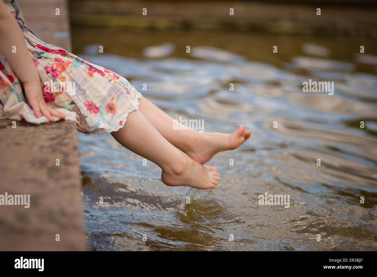 Ragazza immergendo i suoi piedi in acqua Foto Stock