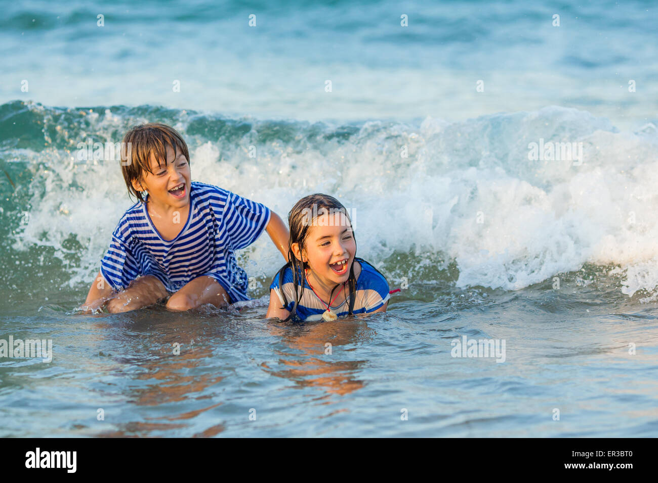 Due bambini felici che giocano in mare Foto Stock