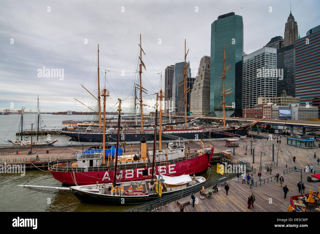 La gente a piedi nel punto di riferimento porto marittimo situato accanto a Wall Street e il centro finanziario di brutto tempo Foto Stock