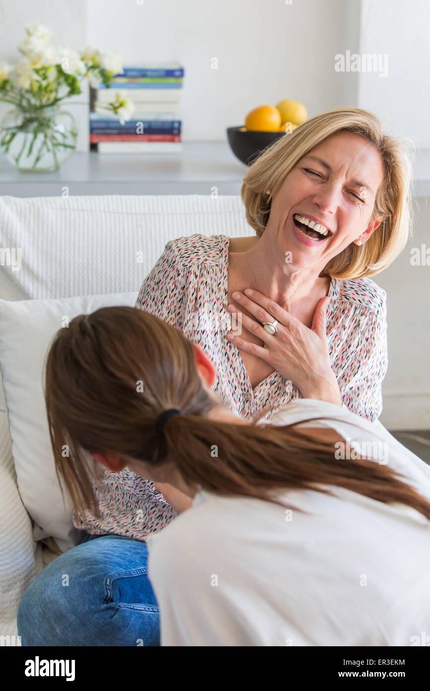 Due donne ridere; guardando sopra la spalla dietro una donna. Foto Stock