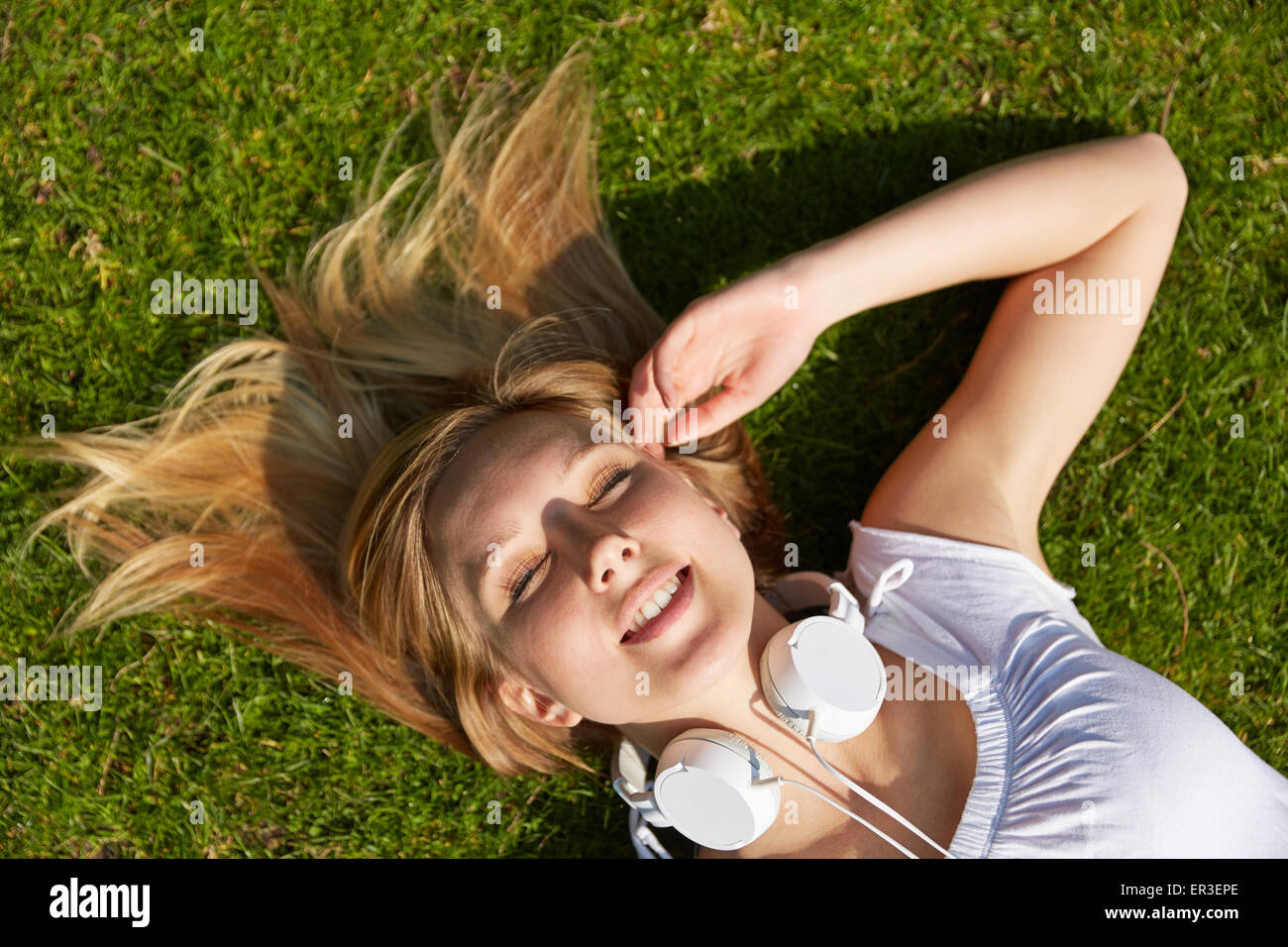 Giovane donna bionda posa in estate in erba verde in un parco Foto Stock