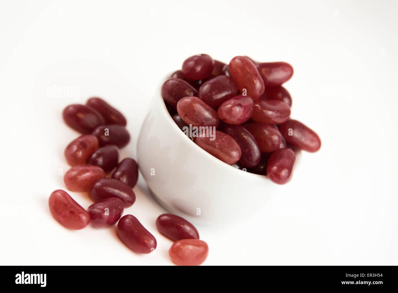 Viola e rosso jellybeans su una piastra bianca e sfondo bianco Foto Stock