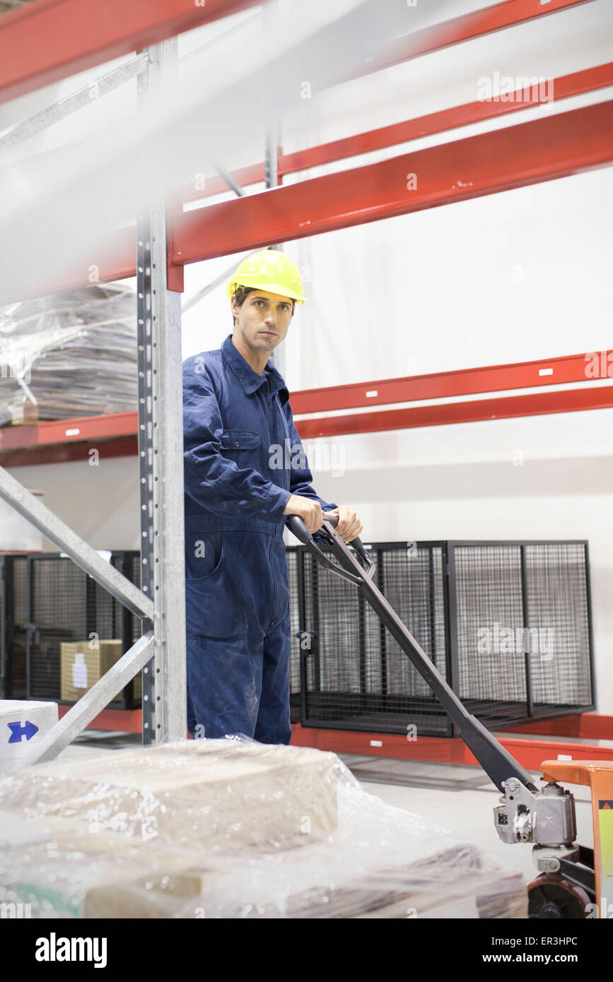 Funzionamento del lavoratore martinetto pallet in magazzino Foto Stock