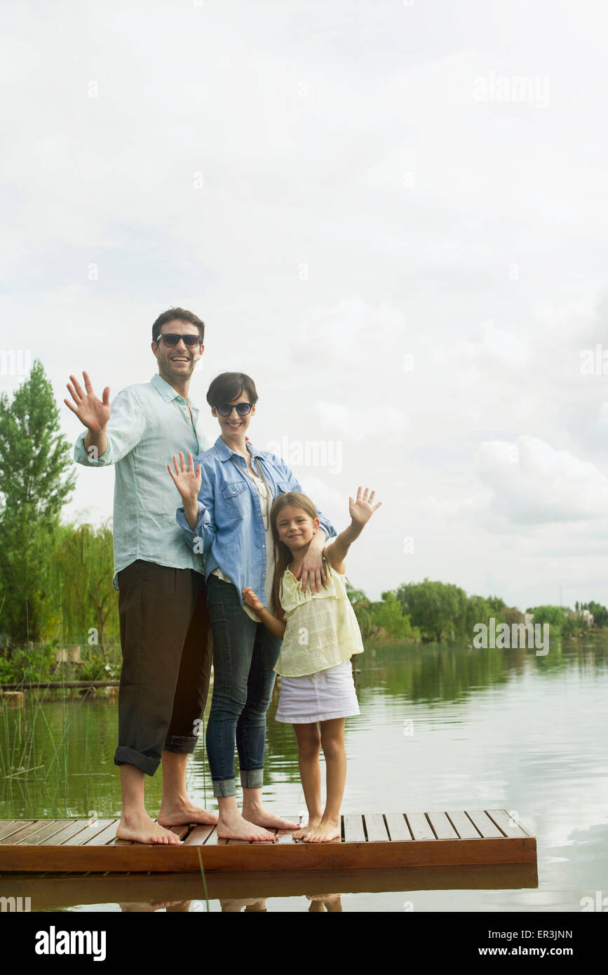 Famiglia permanente sulla dock sventolando Foto Stock