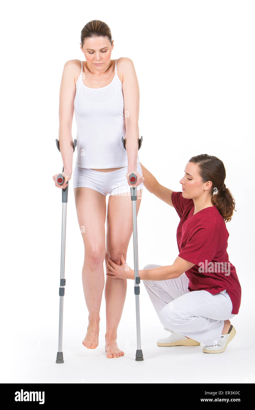 Donna con la stampella presso il fisioterapista facendo riabilitazione delle gambe Foto Stock