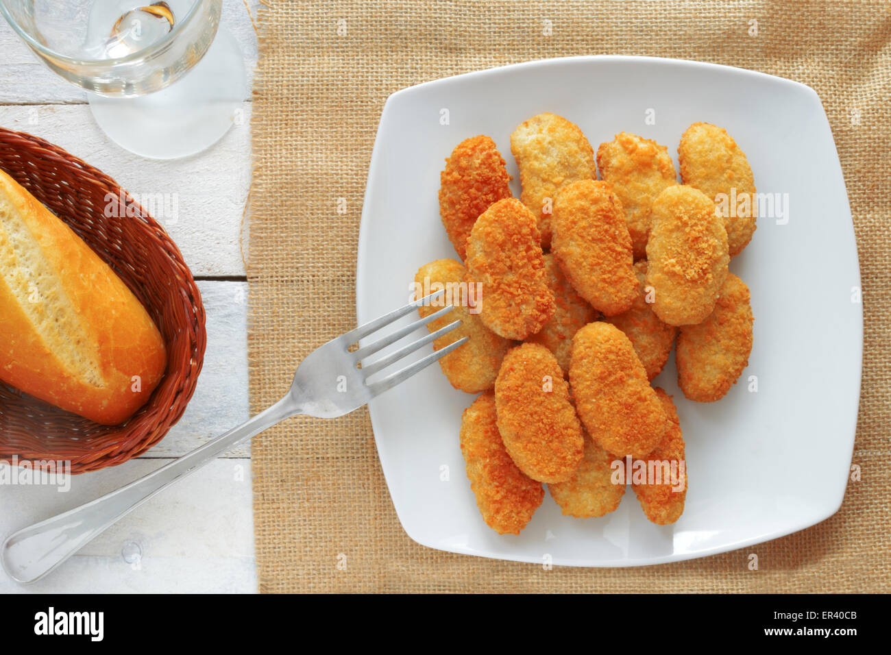 Pepite di pollo servito in una ciotola bianco su bianco tavola in legno di una cucina rustica Foto Stock