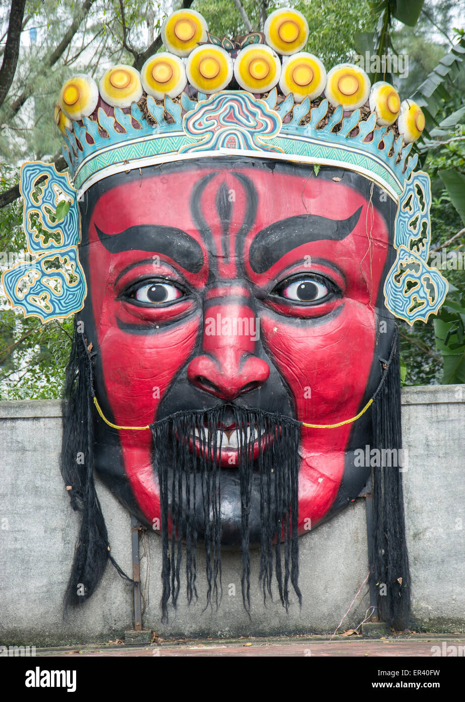 Un grande oriental faccia rossa con la statua di corona sulla parete Foto Stock