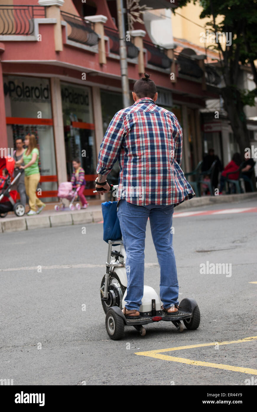 Uomo su scooter elettrico in sella a road Foto Stock