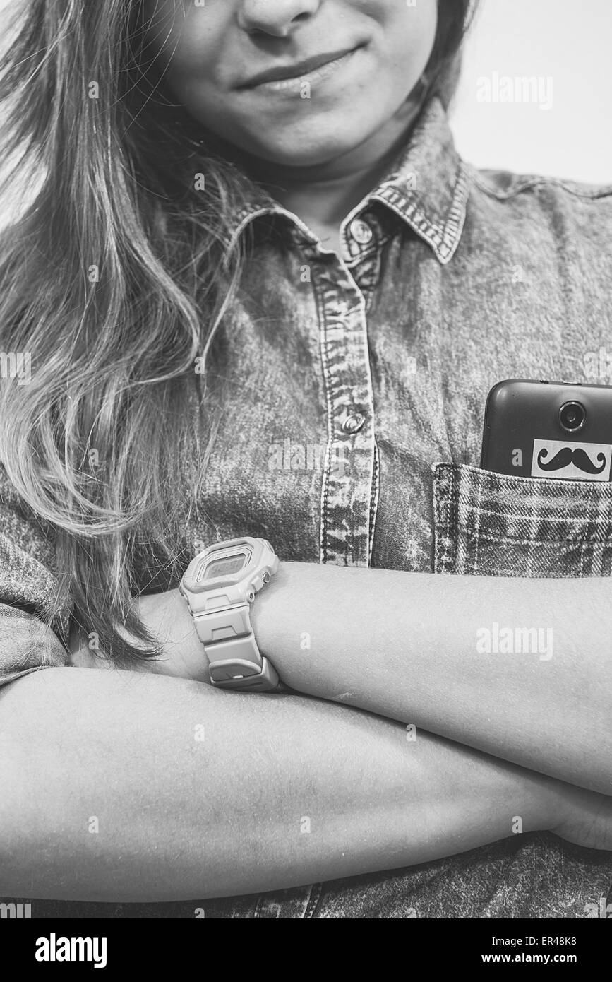 Ragazza adolescente con un telefono nella sua tasca con le mani incrociate e capelli visibili. Foto Stock