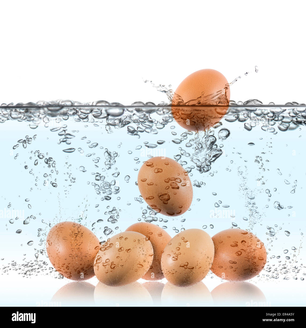 Uova immerse in acqua bollente per cucinare Foto Stock