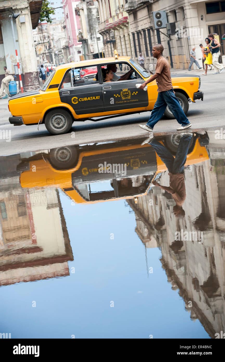 L'Avana, Cuba - Giugno, 2011: Vintage Russian Lada auto taxi riflette accanto al passaggio di pedoni di una pozzanghera su una strada nel Centro. Foto Stock