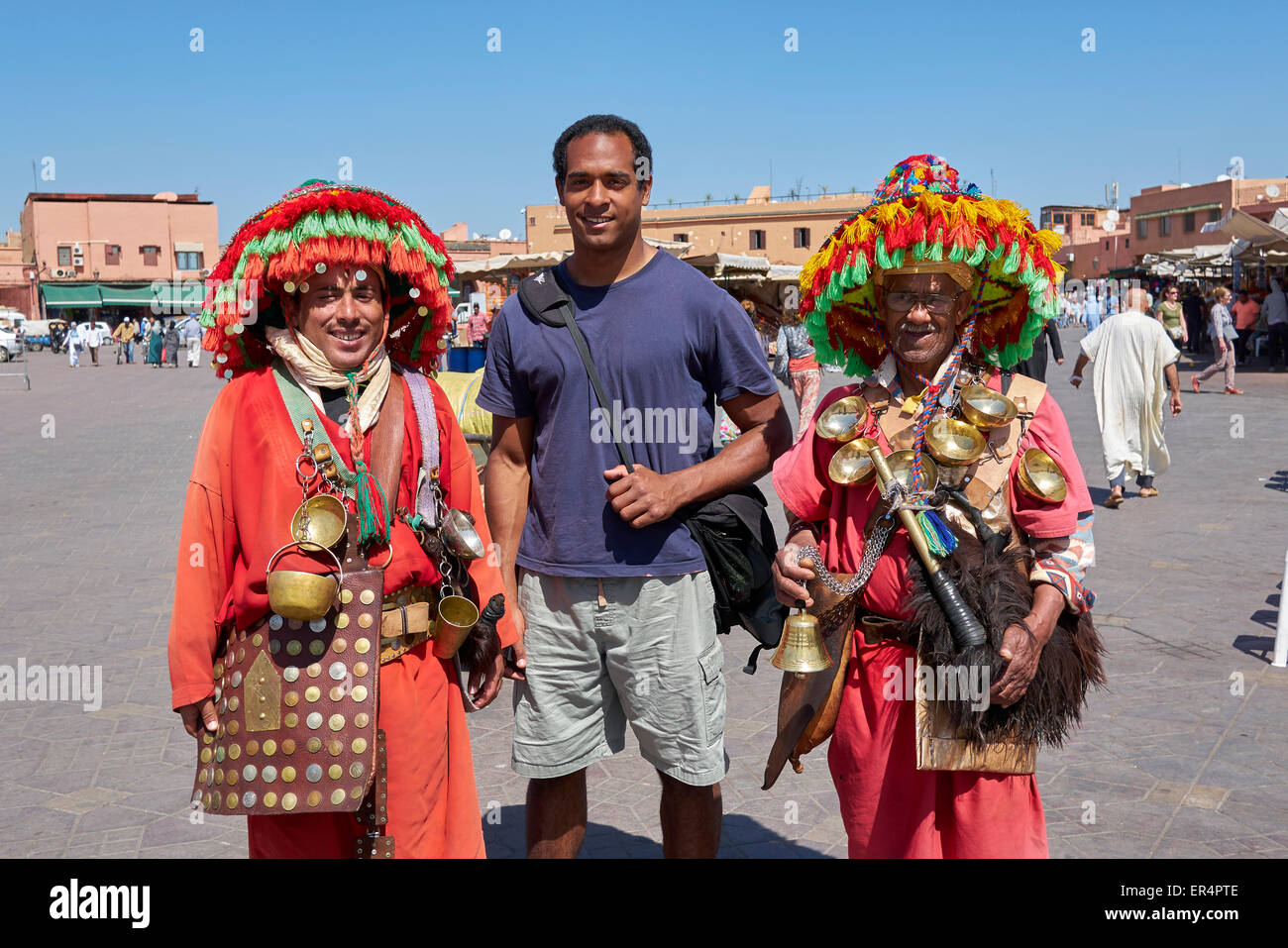 Tradizionali Berbere uomini indossare cappelli in Djemaa el Fna market place, con un turista , Marrakech, Marocco Foto Stock
