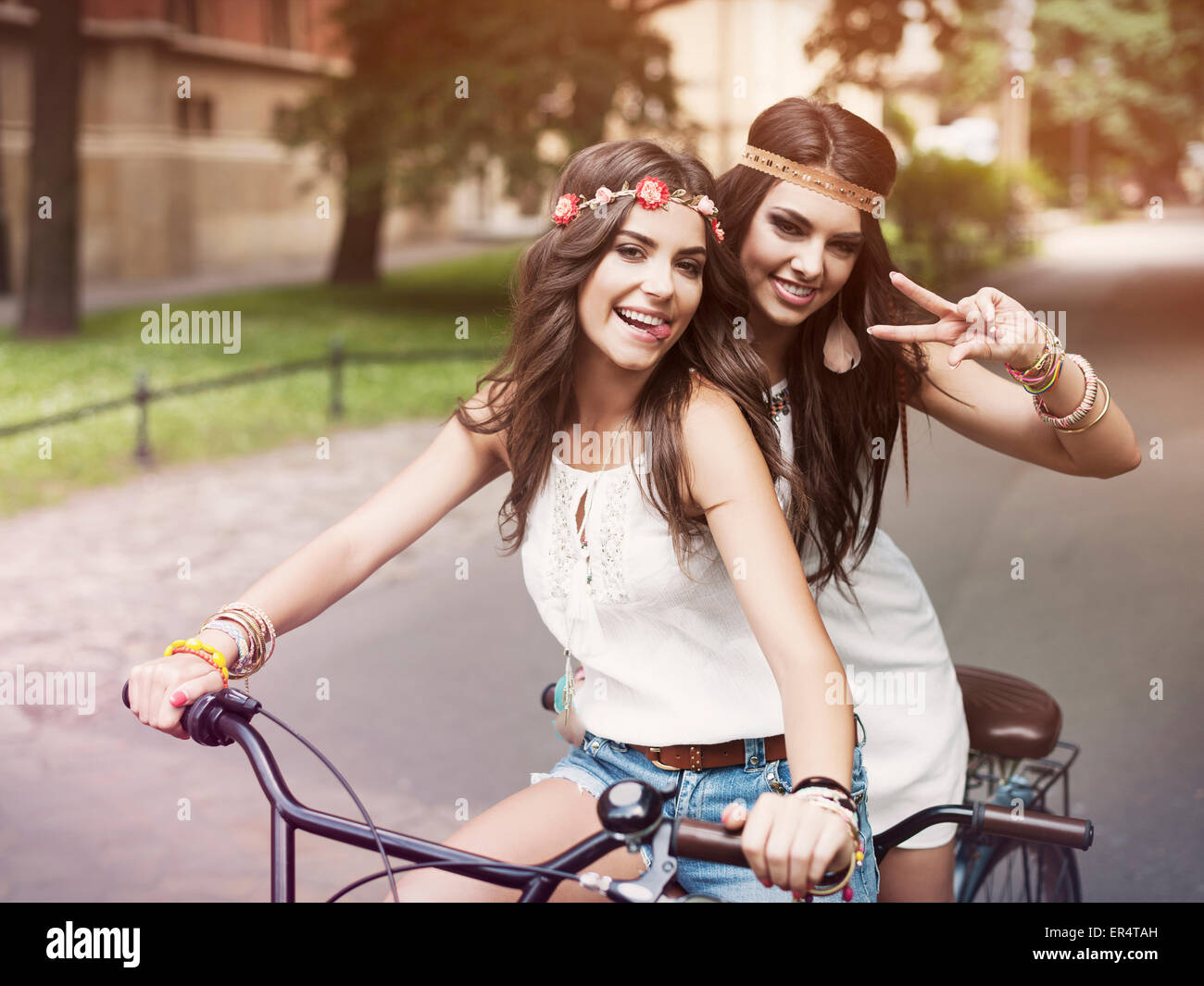 Ritratto di funny boho ragazze su una bicicletta in tandem. Cracovia in Polonia Foto Stock