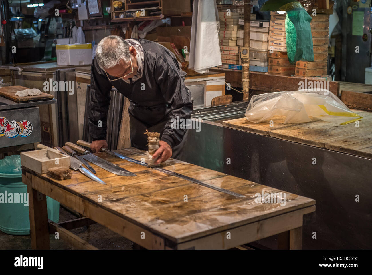 TOKYO, Giappone - Novembre, 22, 2014: giapponese vecchio uomo con coltelli tradizionali a Tsukiji, il più grande pesce e frutti di mare mercato in t Foto Stock