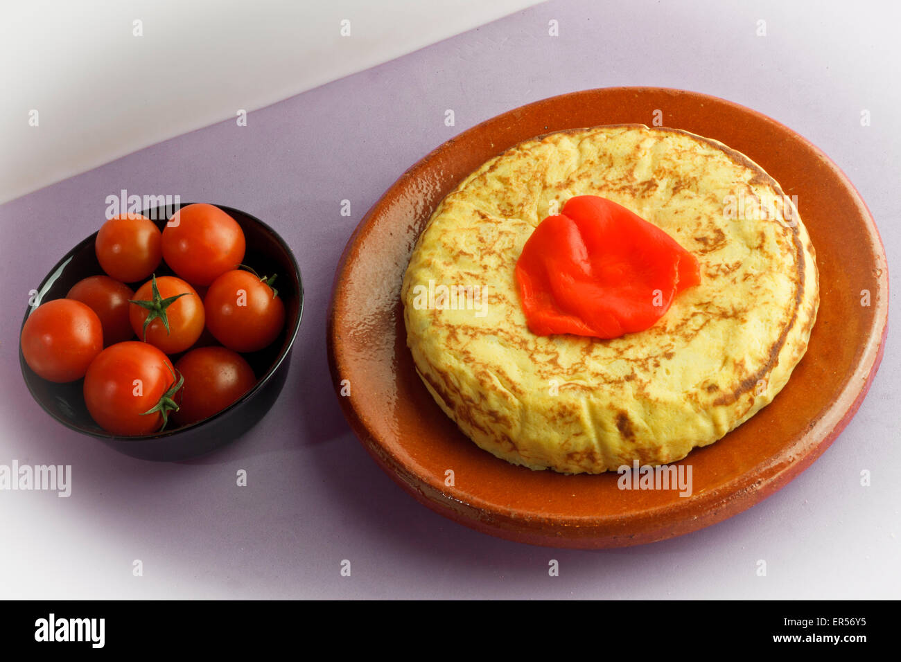 Frittata spagnola con il pepe e pomodori ciliegia su una tazza Foto Stock