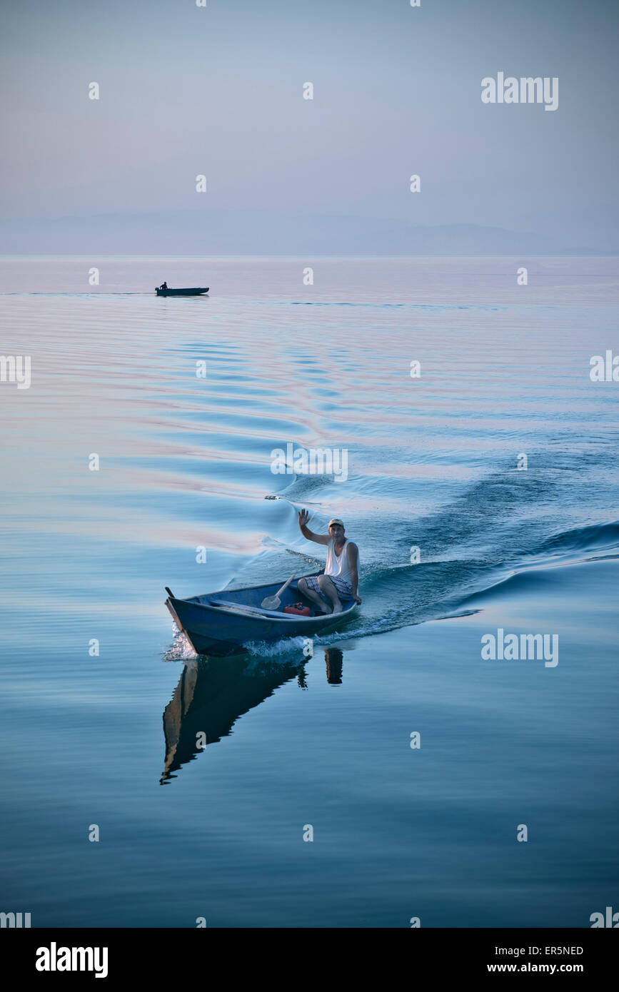 Pescatore in barca salutando la telecamera, Murici, il Lago di Scutari Parco Nazionale, Montenegro, dei paesi dei Balcani occidentali, Europa Foto Stock