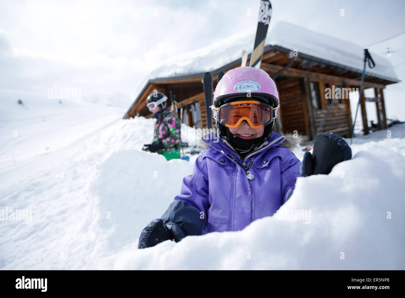 Due bambini nella neve nella parte anteriore di una capanna, stazione sciistica Ladurns, Colle Isarco, Alto Adige, Italia Foto Stock
