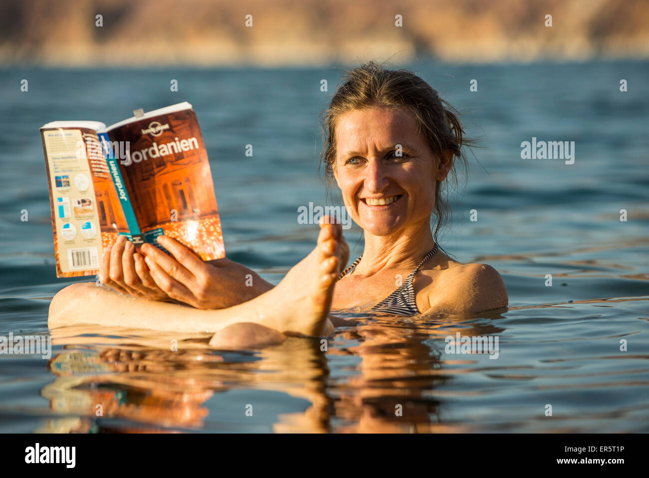 Donna che legge un libro guida nel Mar Morto, Giordania, Medio Oriente Foto Stock