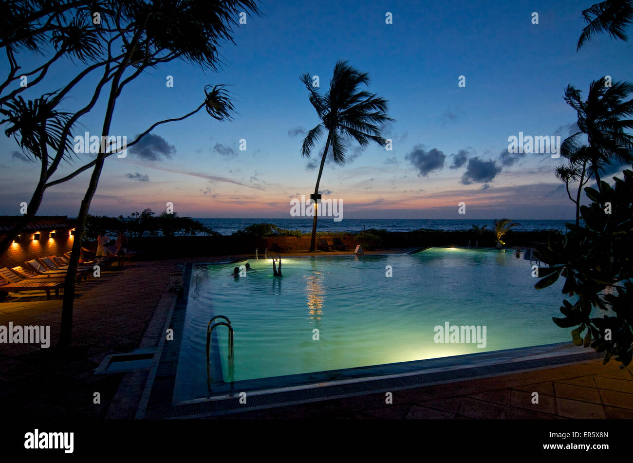 Piscina che si affaccia sul mare dopo il tramonto, Ranweli Holiday Village Resort, Waikkal bei Negombo, Sri Lanka Foto Stock