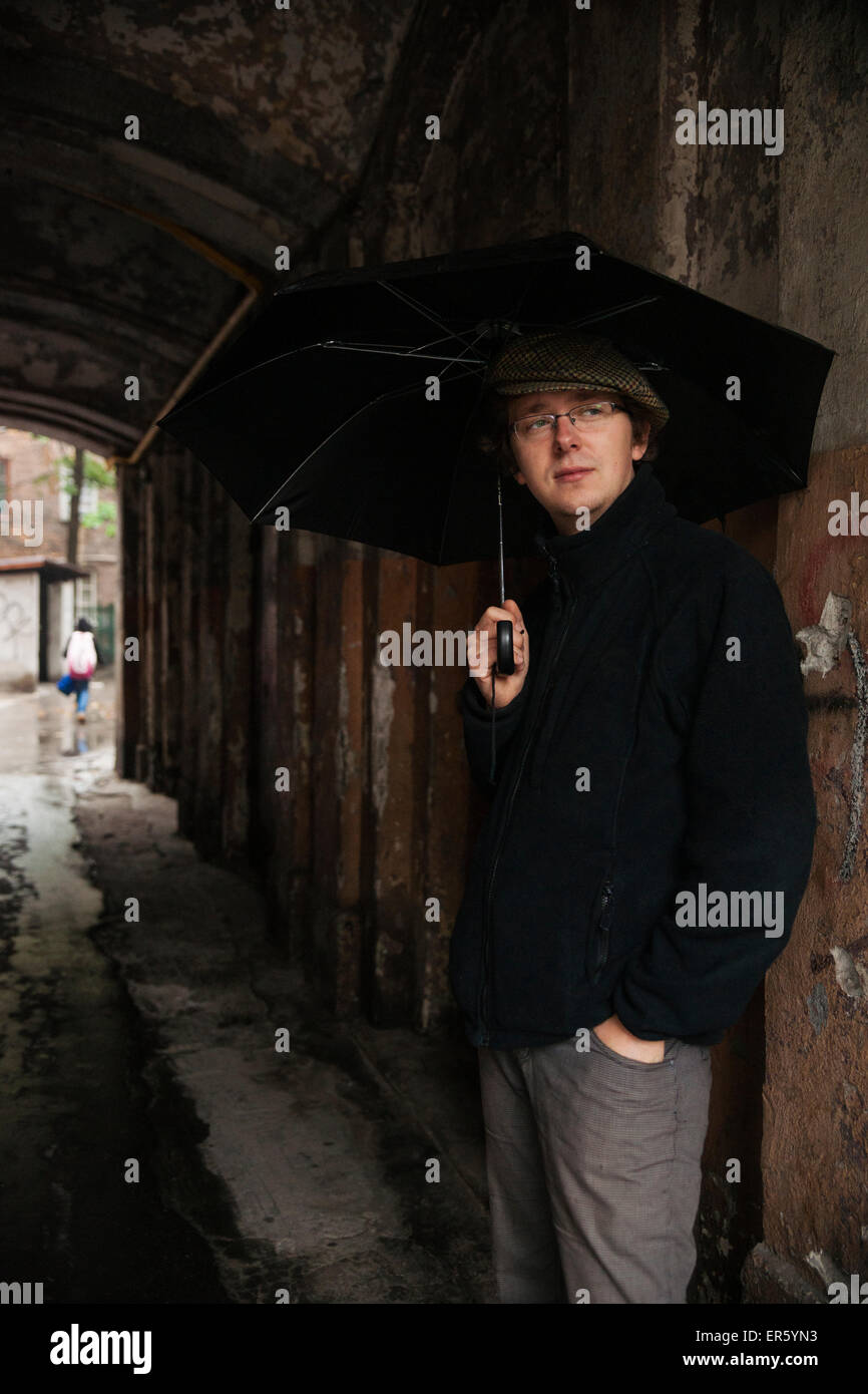 Caucasica uomo polacco tenendo un ombrello nero in ingresso alla porta di appartamento edificio, distretto di Praga, Varsavia, Polonia, Europa Foto Stock