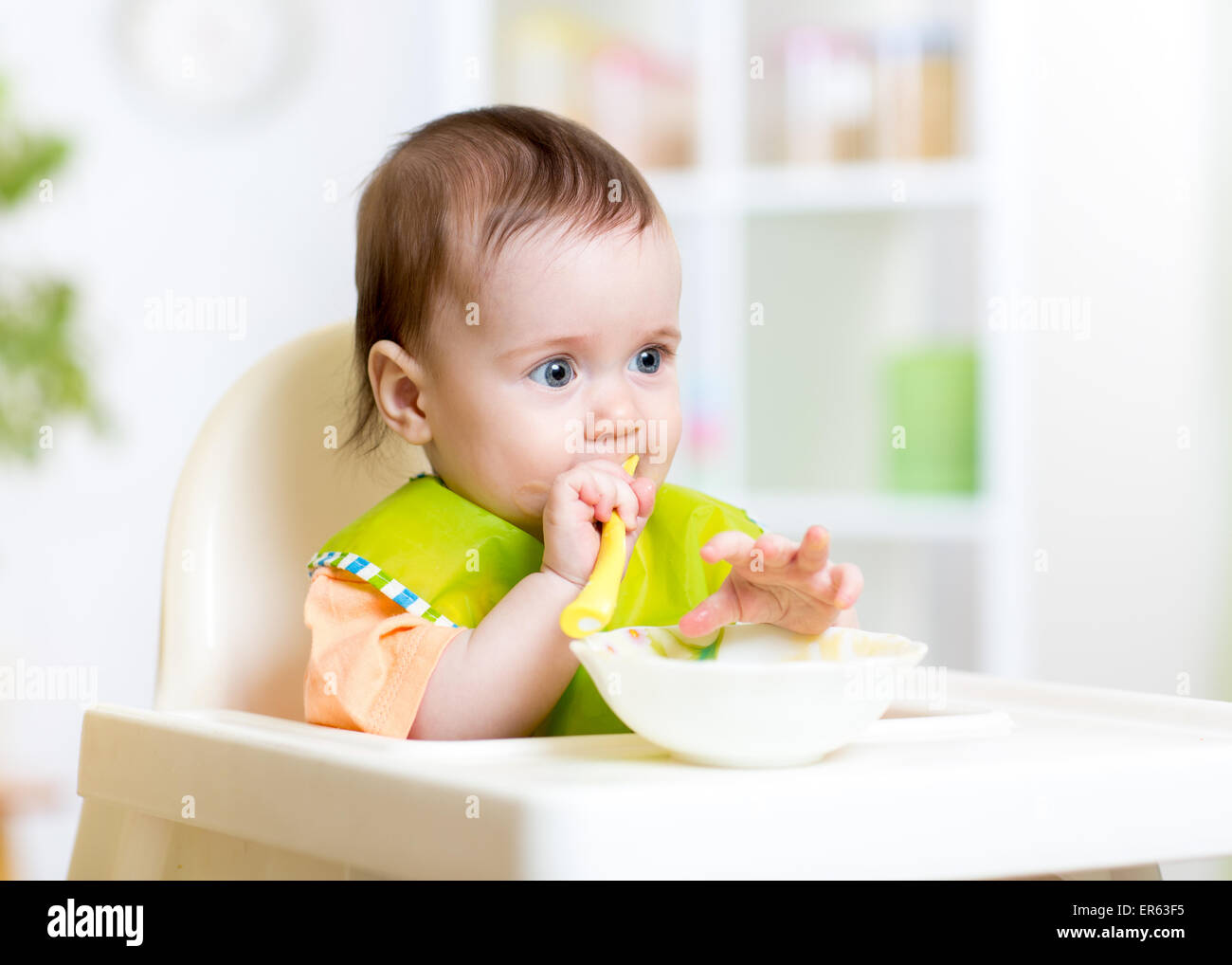 Allegro happy baby bambino seduto in poltrona con un cucchiaio Foto Stock