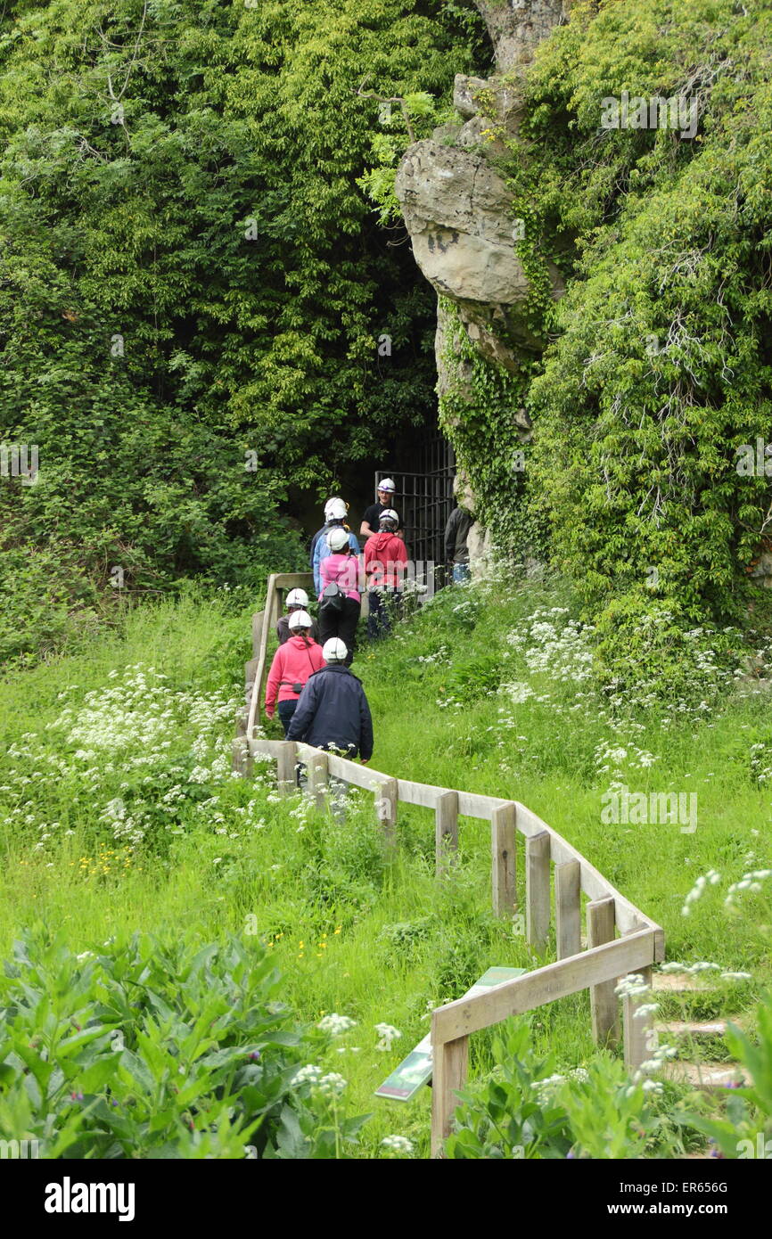 Visitatori entrare in una grotta durante un tour di Creswell Crags sul confine del Derbyshire e Nottinghamshire, England Regno Unito Foto Stock