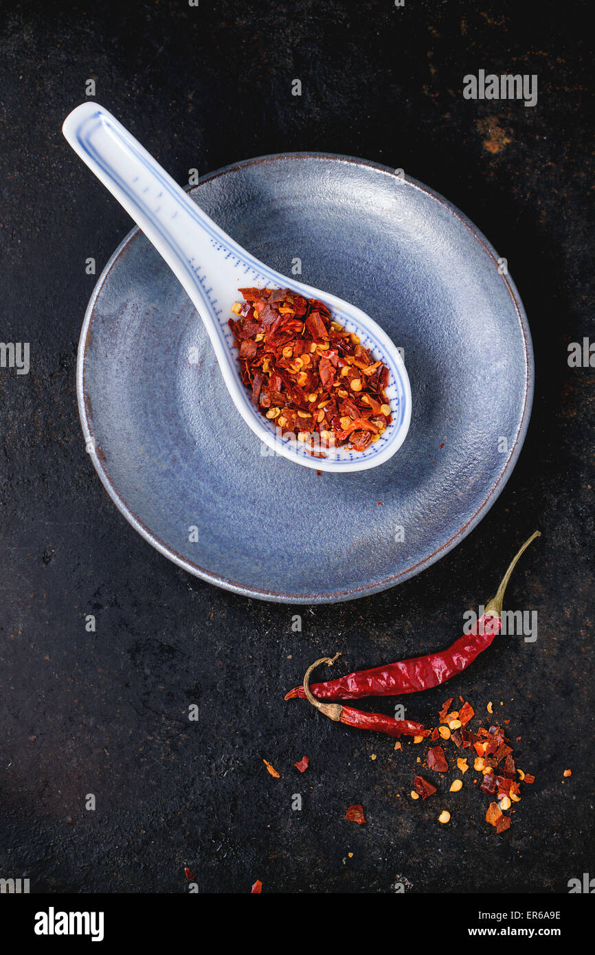 Assortimento di tutto asciutte e scaglie red hot chili peppers in cucchiaio di ceramica su sfondo nero Foto Stock