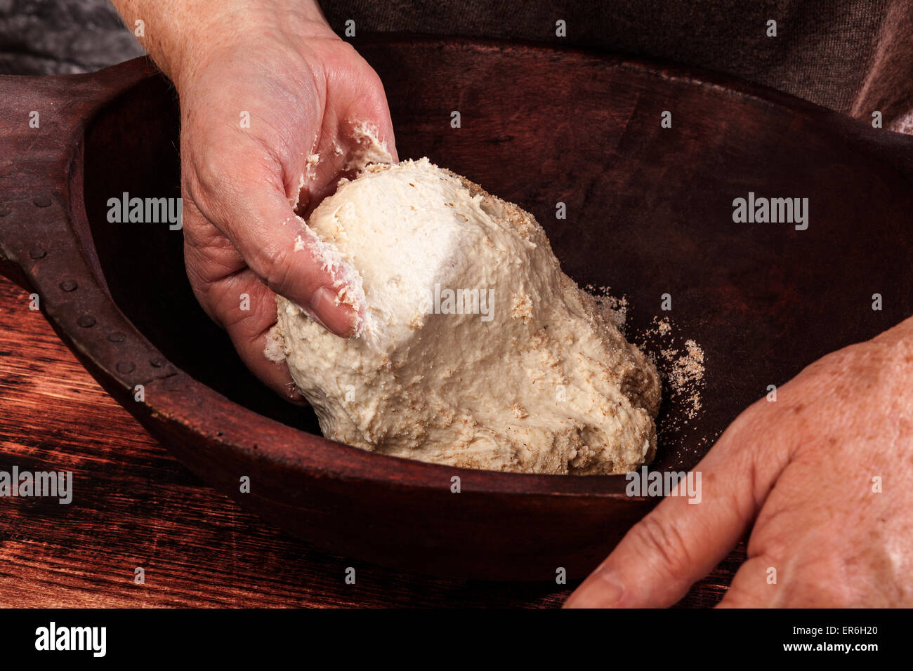 Vecchio mani femminili impastare tutta la pasta di grano in vintage ciotola di legno su sfondo di legno. Tradizionale Cottura sana, rustico vintage Foto Stock