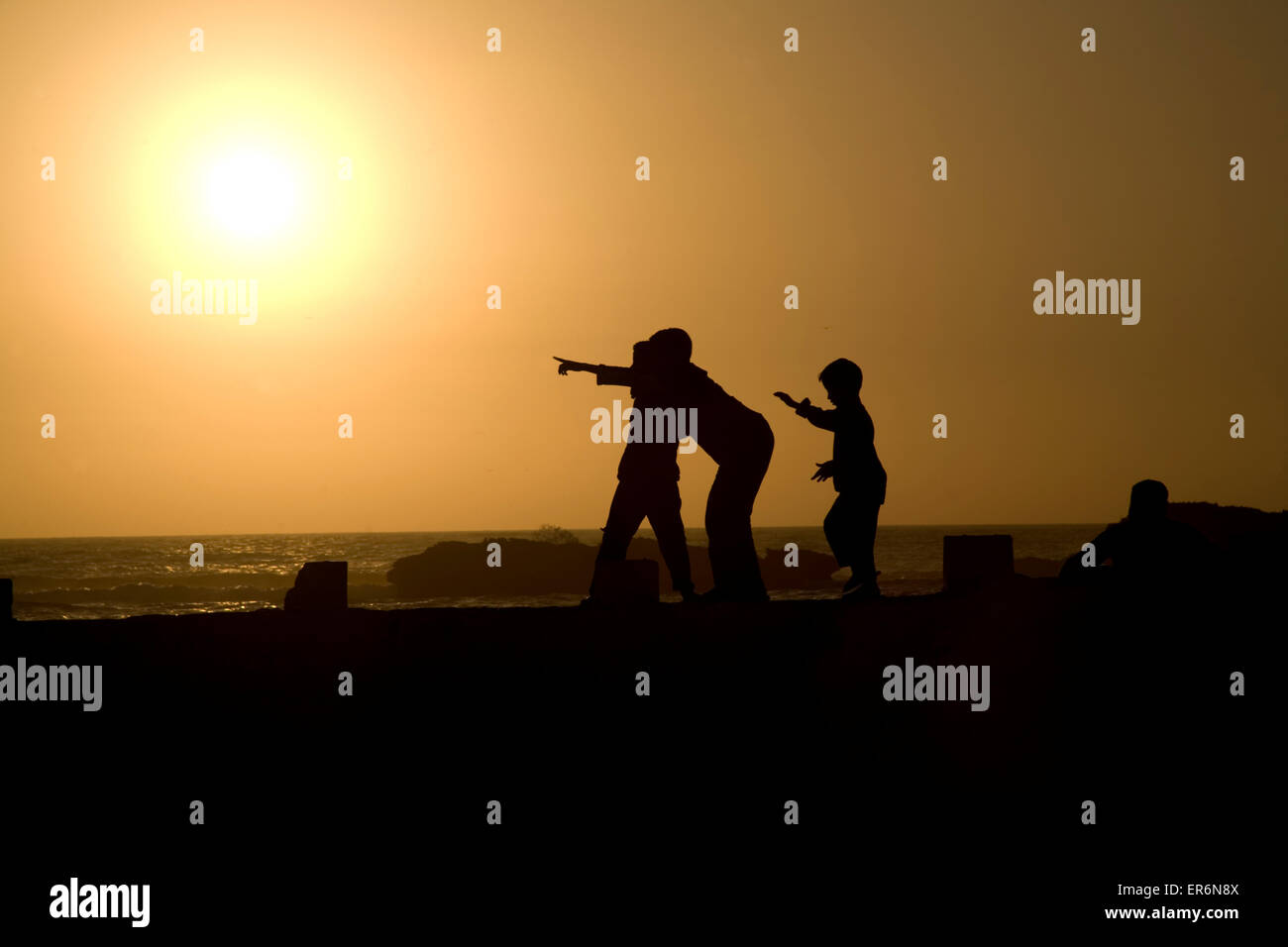 Silhouette di ragazzi che giocano al tramonto sulla parete del porto di Essaouira, Marocco, Africa Foto Stock